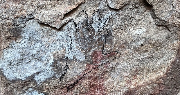 El dibujo fue ejecutado con carbón y consta de tres manos sobre las pinturas rupestres del lugar.